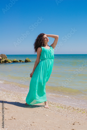 Young girl on the beach in summer in a beautiful dress 