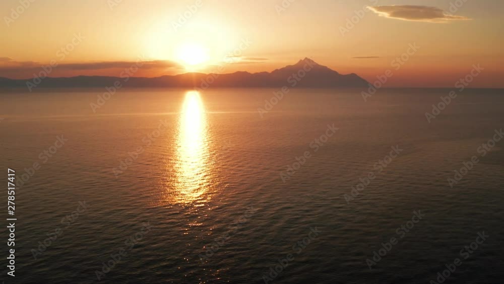 Aerial view of a slide from the drone on the panorama of the sea surface and the silhouette of Mount Athos, Greece in the bright light of the sunrise in the early morning. Holy Mount Athos in Greece Aerial view of a slide from the drone on the panorama of the sea surface and the silhouette of Mount Athos, Greece in the bright light of the sunrise in the early morning. Holy Mount Athos in Greece