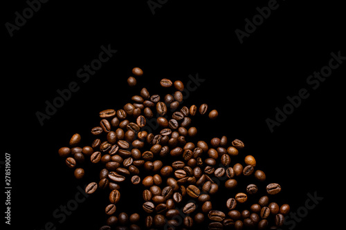 Scattered grains of roasted, fragrant coffee on a black background, isolation, flat-lay, copy space