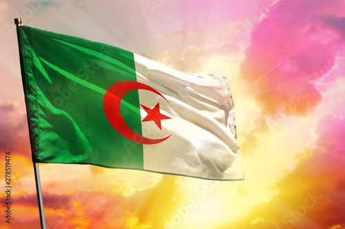 Fluttering Algeria flag on beautiful colorful sunset or sunrise background. Success concept.