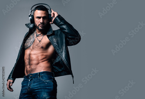 Music in headphones. Bearded hispanic man with muscular torso wearing headphones. Brutal latino man listening to music in audio headphones. Confident guy in dj headphones, copy space