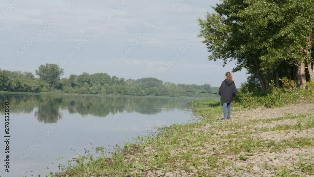 cute teenag girl fishing on river bank standing on the sand and holding fishing rod. cute teenag girl fishing on river bank standing on the sand and holding fishing rod.