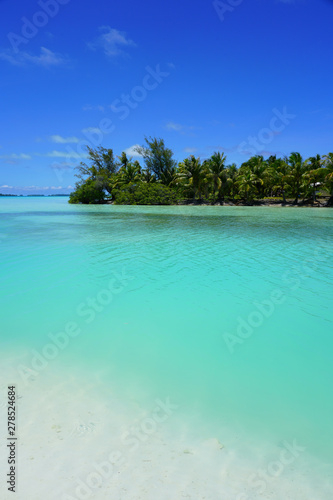View of a tropical landscape with palm trees, white sand and the turquoise lagoon water in Bora Bora, French Polynesia, South Pacific © eqroy