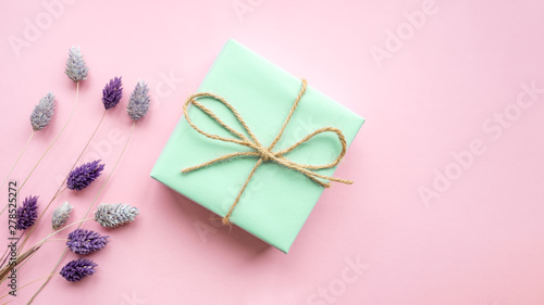 Green gift box with ribbon on a pink background .