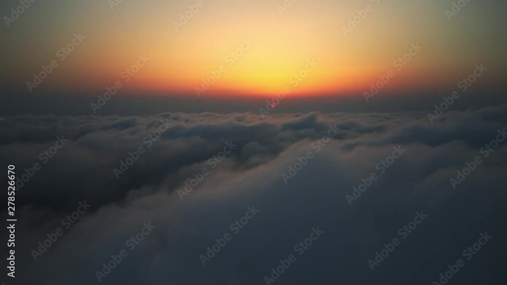 Hyper lapse from the air with a drone on the picturesque view of the bright crimson sunset over the horizon with clouds through the moving dense fog. Bright sun disc in sunset Hyper lapse from the air with a drone on the picturesque view of the bright crimson sunset over the horizon with clouds through the moving dense fog. Bright sun disc in sunset