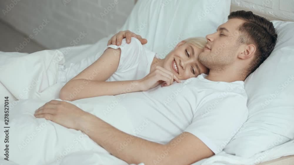 beautiful woman stroking and embracing smiling sleeping man in bed beautiful woman stroking and embracing smiling sleeping man in bed