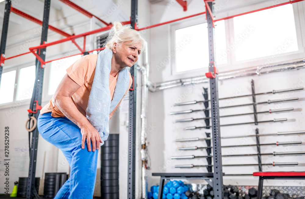 Senior woman at the gym suffering from pain in knee