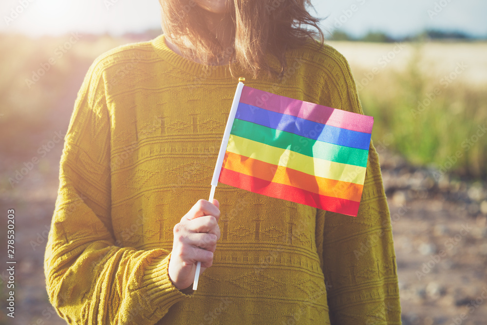 young woman wearing yellow sweater holding lgbt rainbow flag outside, same  sex couples, freedom, love, equal rights concept Stock Photo | Adobe Stock