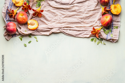 Food background with fresh whole and half peaches on kitchen towel with leaves, flowers and copy space for your design or product , top view. Flat lay. Horizontal. Border