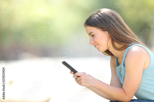 Serious woman checking phone online content in a park