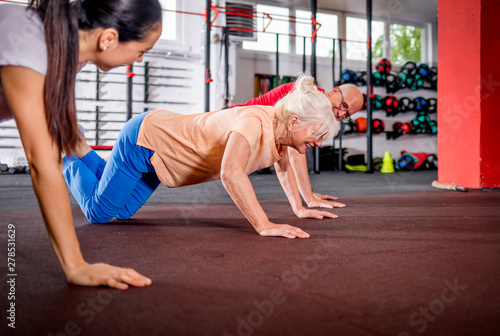 Senior people workout with personal trainer at the gym
