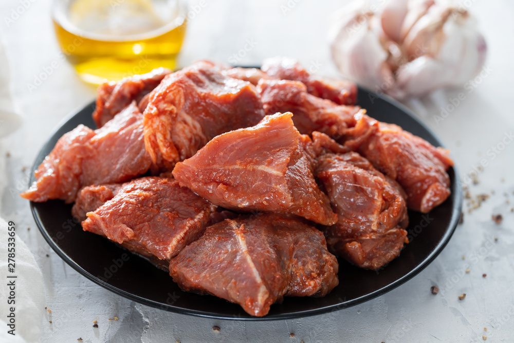 raw pork in marinate on black plate on ceramic background raw pork in marinate on black plate on ceramic background