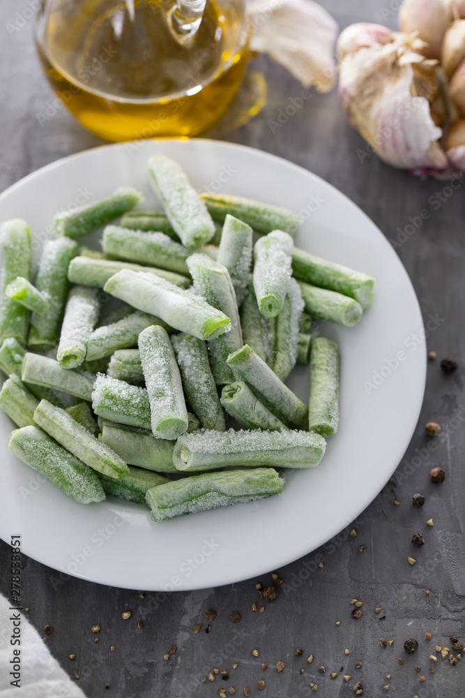 frozen green beans on white plate on ceramic background frozen green beans on white plate on ceramic background