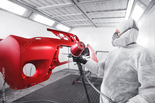 Schilderij op canvas Male worker in protective clothes and mask painting car using spray paint
