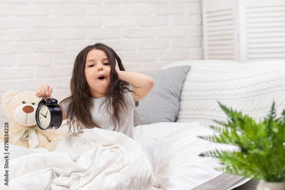 cute surprised little child girl in pyjamas with clock in bed. good morning cute surprised little child girl in pyjamas with clock in bed. good morning