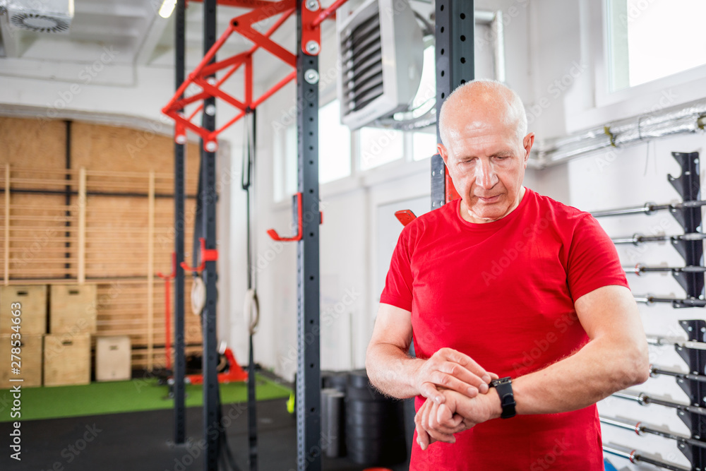 Senior man at the gym using smartwatch Senior man at the gym using smartwatch
