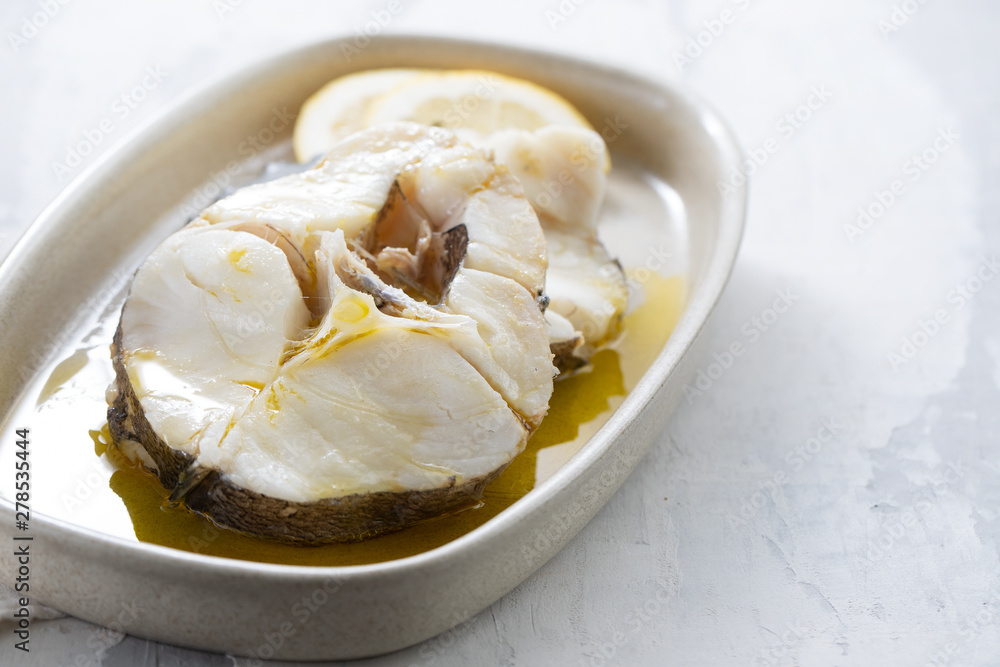 boiled fish with olive oil in dish on ceramic background boiled fish with olive oil in dish on ceramic background