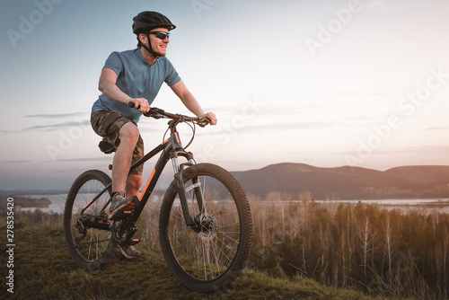 young man on the mountain bike at sunset.