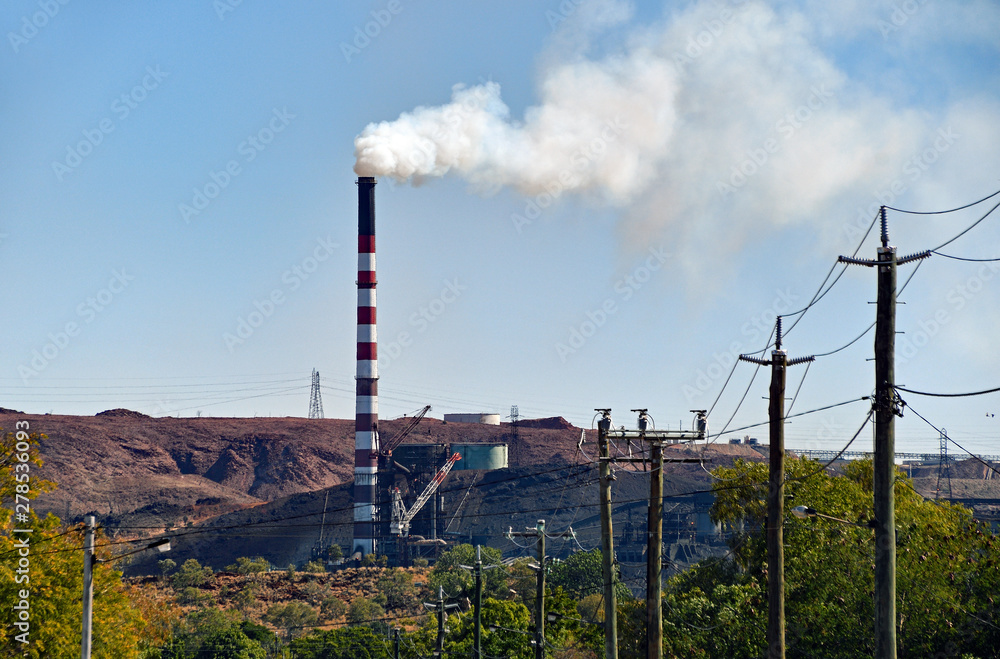 Industry town with mining chimney bellowing white smoke against blue sky. Industry town with mining chimney bellowing white smoke against blue sky.