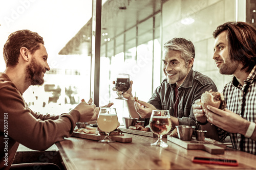 Sticker Joyful males spending time together in cafe