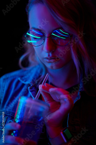 Woman with coctail drink in neon lighting