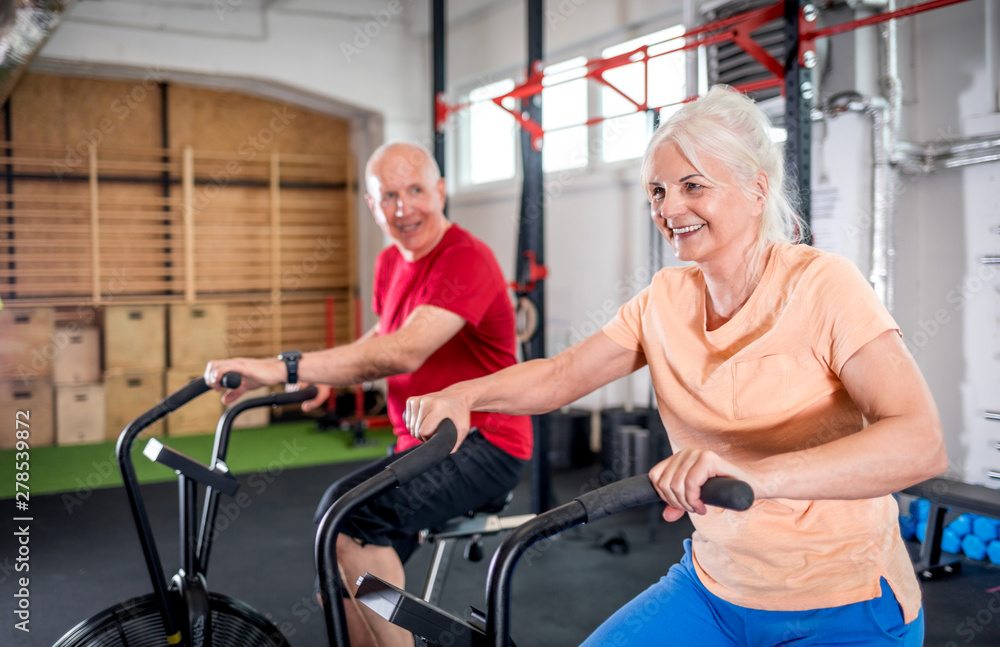 Senior couple biking at the gym Senior couple biking at the gym