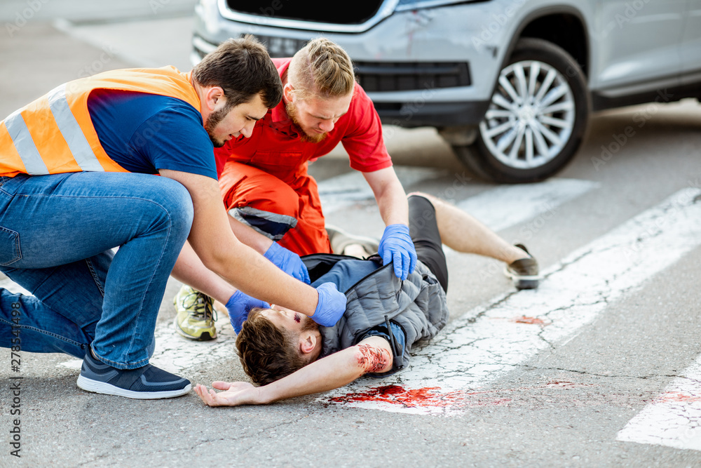 Medic with car driver applying first aid to the injured man lying on the  pedestrian crossing after the road accident Photos | Adobe Stock