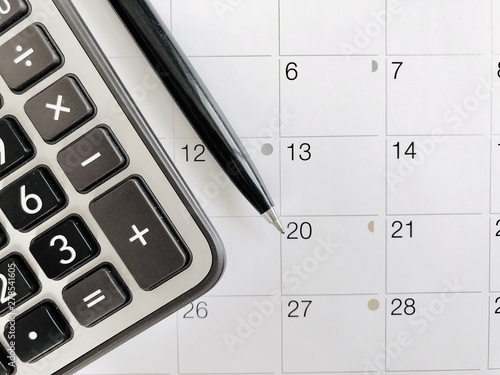 Business,finance, taxes, accounting, wages, payroll or money planning concepts : Top view or flat lay of calculator and pen on calendar