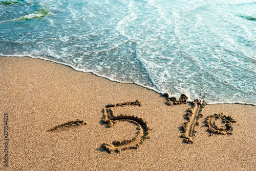 inscription on the sand minus 5 percent, 5 %, sea wave on the sand with the inscription