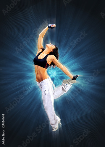 Young beautiful athletic woman jumping dancing modern style dance hip-hop on studio on wall background  photo