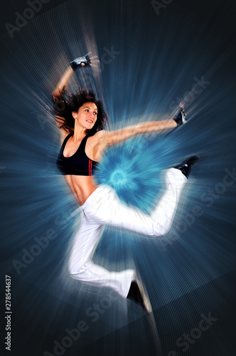 Young beautiful athletic woman jumping dancing modern style dance hip-hop on studio on wall background 