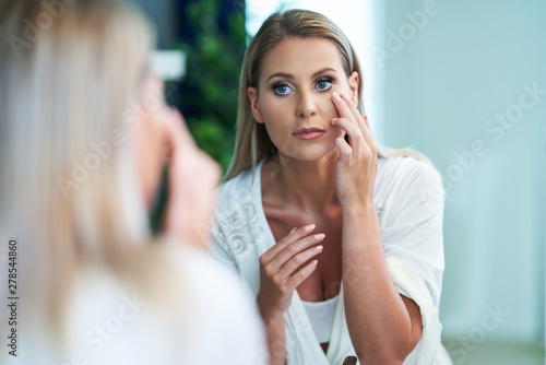 Beautiful woman applying face cream in the bathroom
