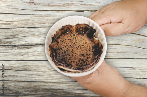 Hand drip coffee with filter on wood background