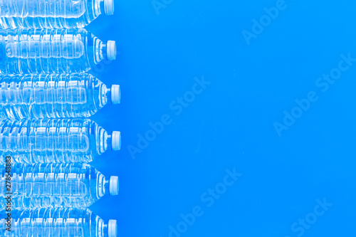 Pure water in plastic bottles on blue background top view copyspace