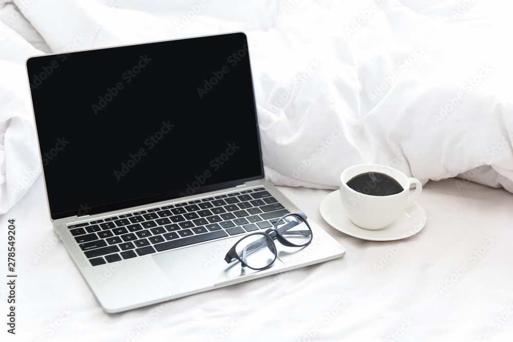 The laptop and alarm clock in the morning on a white bed. copy space. Lifestyle Concept The laptop and alarm clock in the morning on a white bed. copy space. Lifestyle Concept