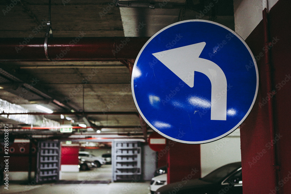 Mandatory turn left road signal inside an underground parking Mandatory turn left road signal inside an underground parking
