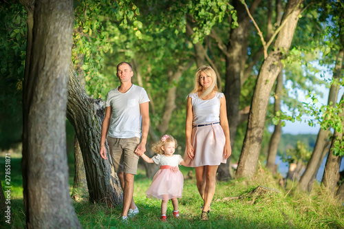 people concept. friendly family walks in a beautiful summer park along the riverbank