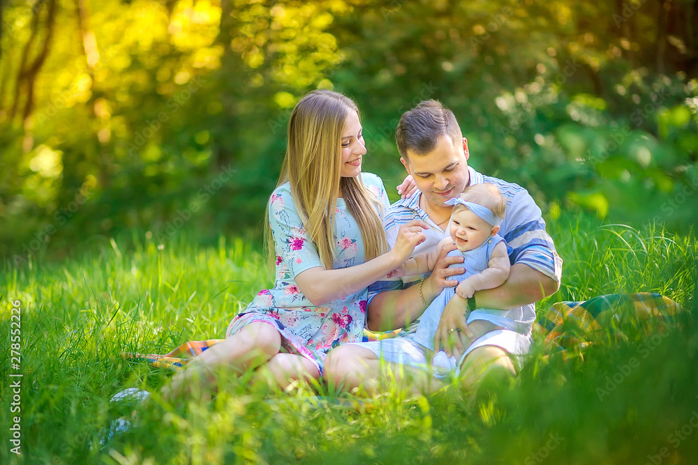 Fototapeta premium friendly family resting in a beautiful summer park. sit on the blanket and play. people concept.