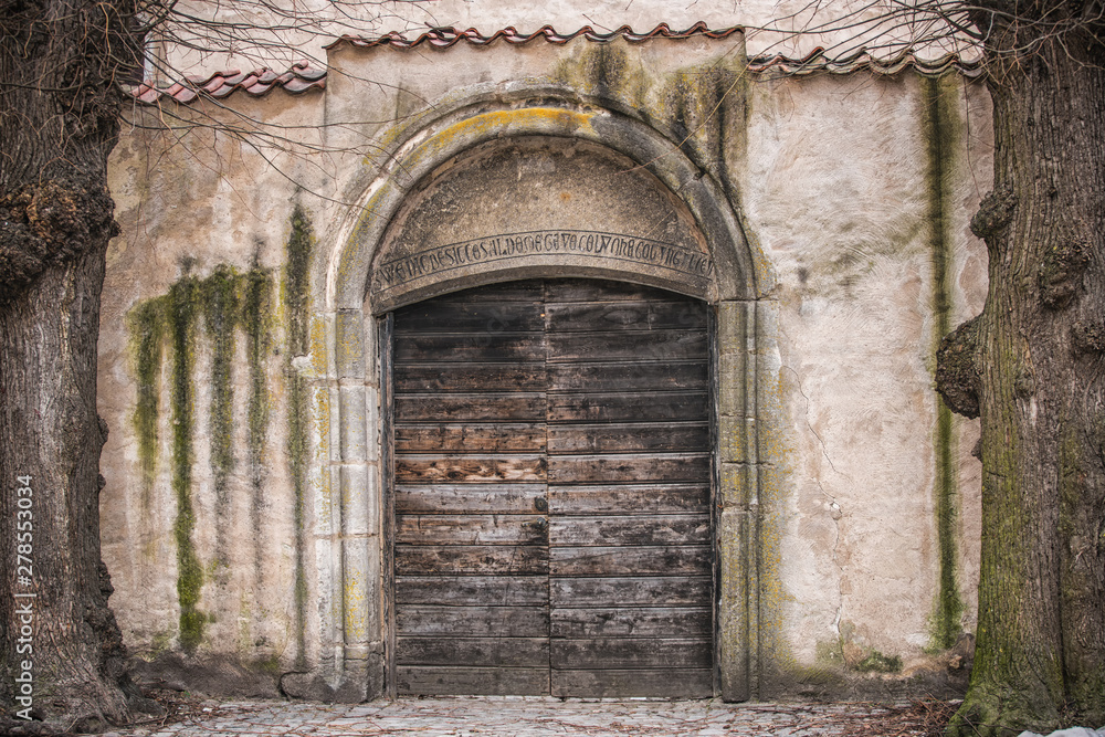 Ancient wooden door in old stone castle wall.