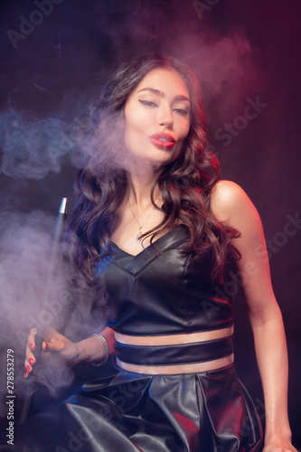 Beautiful woman in smokes hookah or shisha. White cloud vape. Dark background