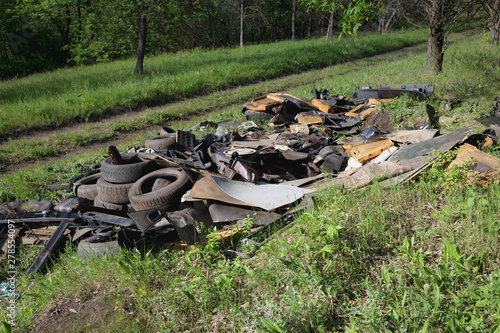 A pile of garbage auto parts in the forest.