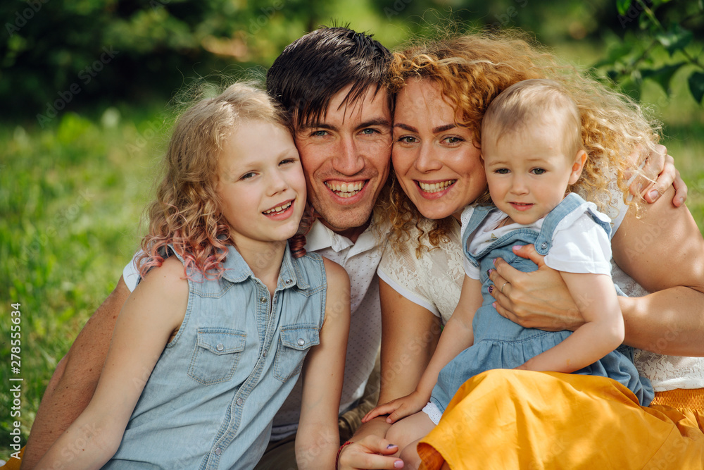 Fototapeta premium Portrait of a family during picnic on grass in the gardens