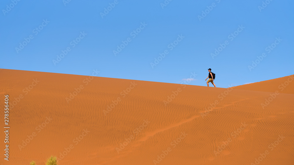 Tourist walks on the scenic dunes of Sossusvlei in the Namib desert, Namibia Tourist walks on the scenic dunes of Sossusvlei in the Namib desert, Namibia