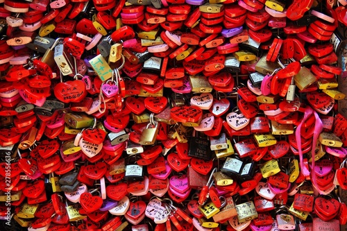 Locked locks of love and loyalty. Wall full of red and pink love locks shaped as hearts and classical locks with writings on each lock, in Verona, Romeo & Julia, Casa di Giulietta House of Julietta