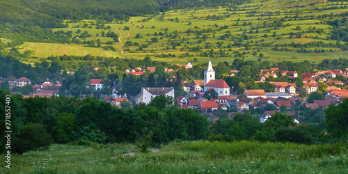 Panorama: Rimetea village (Torocko in Hungarian or Eisenmarkt, Eisenburg, Traschen in German) with white church and traditional Transylvanian houses, at sunrise - view from an elevated location. photo