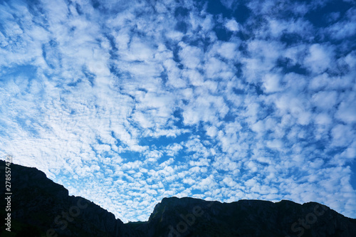 Altocumulus floccus clouds, blue morning sky, and a mountain ridge silhouette. Location: Trascau mountains (part of Carpathians), near Rimetea village, Romania. photo