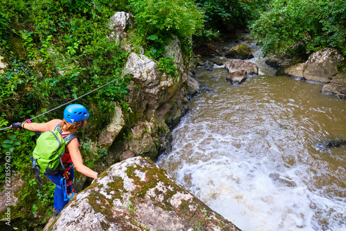 Female tourist with via ferrata gear crossing a cable section above Paraul Racilor in Tureni/Copaceni Gorge, Romania, next to a small waterfall. Popular nature destination from Spring to Autumn. photo