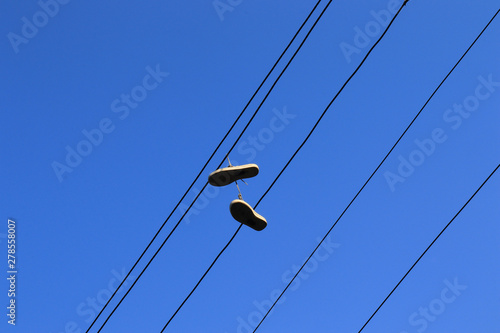 A pair of shoes hanging on the power line cable.