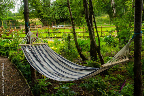 Striped hammock between two trees behind a farm pen