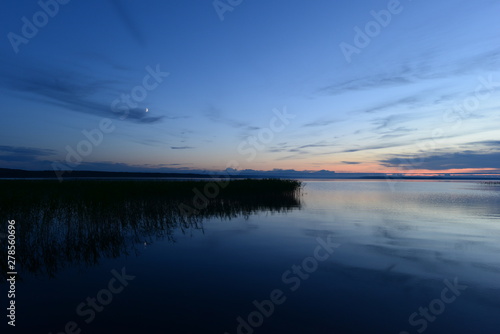 Moonrise in the blue sky before nightfall the in the silence of the lake water